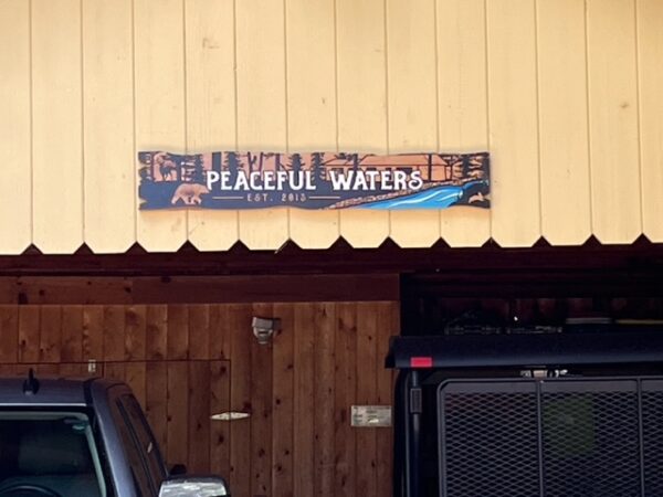 Multicolored Cabin Sign with River Imagery